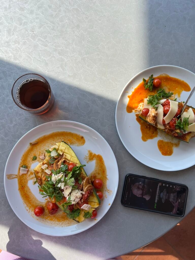 Roasted zucchini boats with cherry tomatoes, mushrooms, herbs, and shaved cheese in tomato sauce.